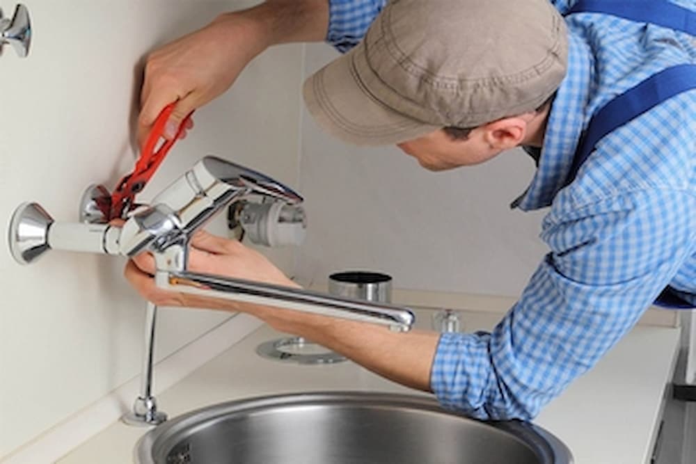 Qualified plumber working on pipe installation in a home